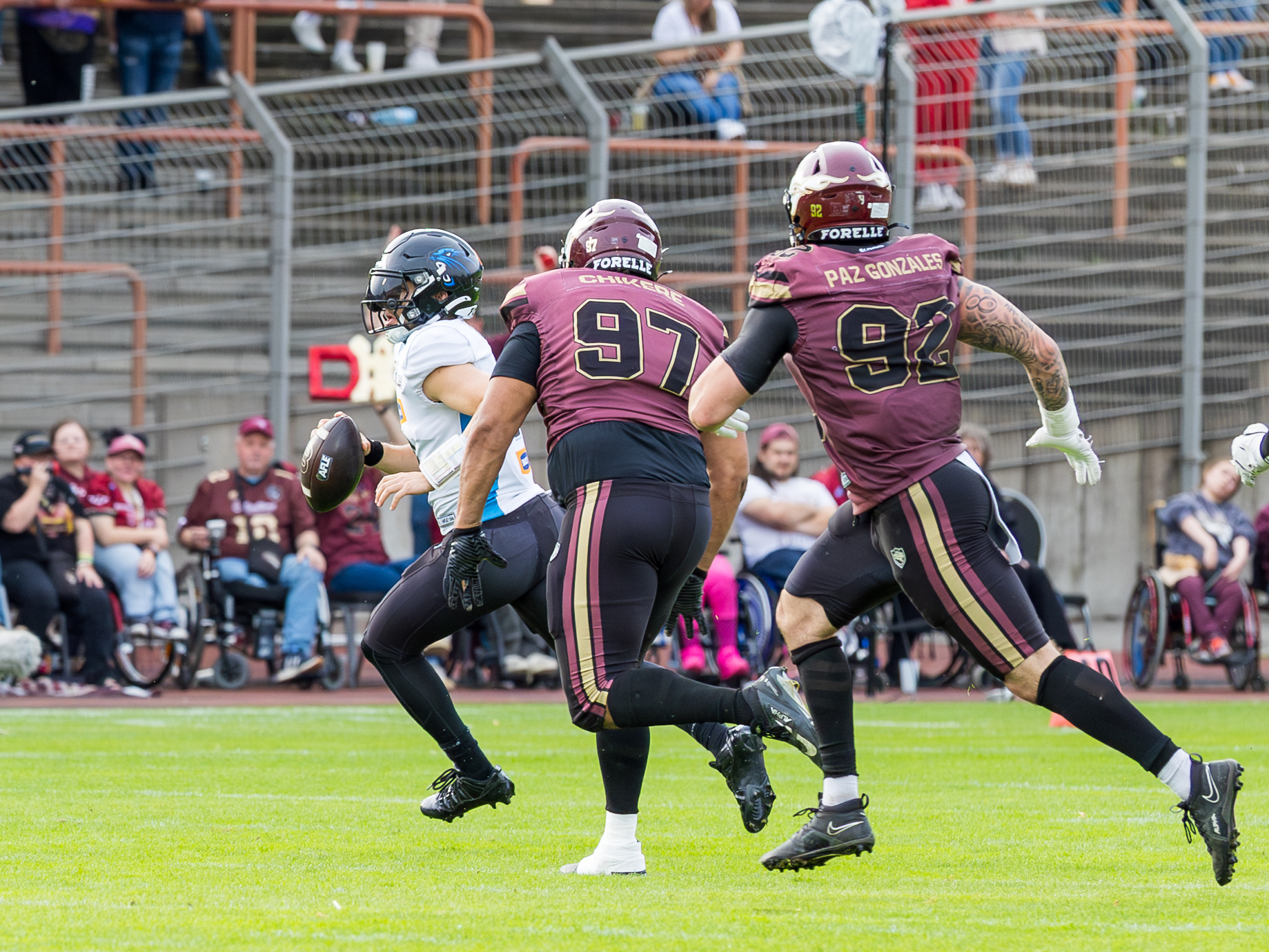#8 Jameson Wang (Quarterback) – Panthers Wroclaw run with the ball. #97 Jason Chikere (Defensive Tackle) – Rhein Fire and #92 Diego Paz González (Defensive End) – Rhein Fire follow him.