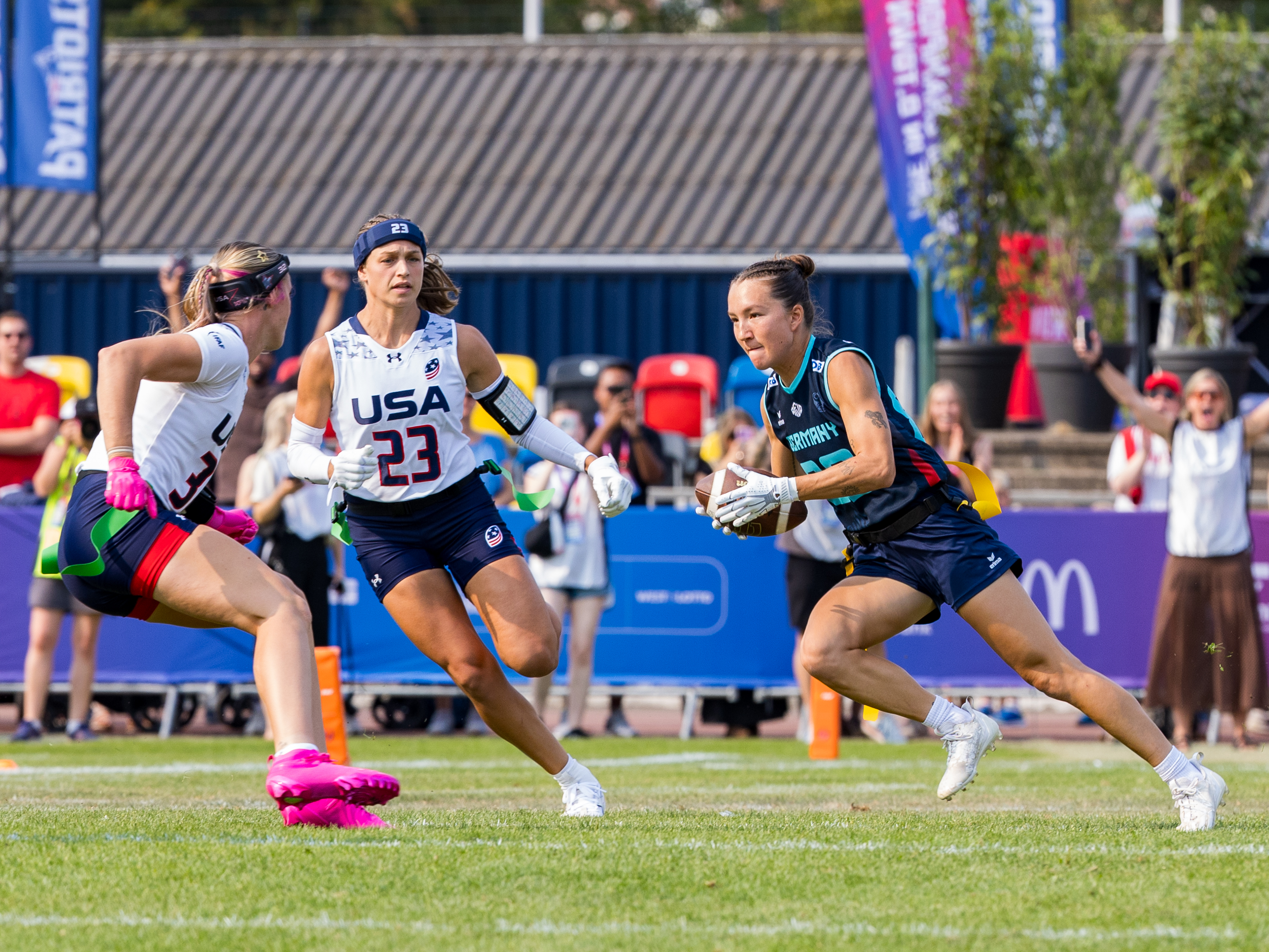 #32 Ashlea Klam (C/S) Team USA Women and #23 Isabella Geraci (WR/S) Team USA Women on the way to tackle #82 Zoe Kwandae Song (DB) Team Germany Women