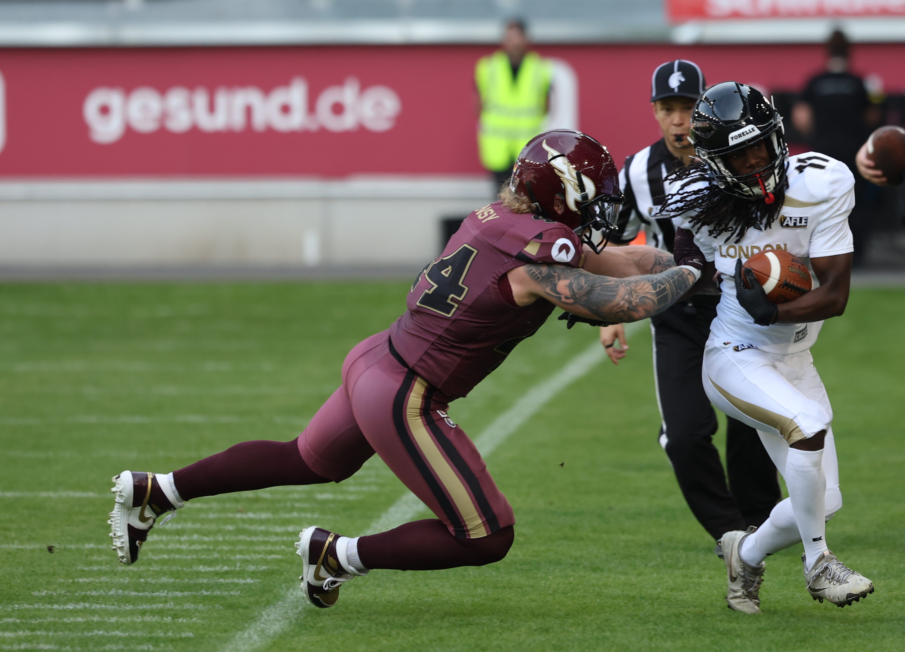 #44 Marius Kensy (Linebacker) – Rhein Fire tackle #11 Leo Walter Dabo (Running Back) – London Warriors out from the field after the catch.