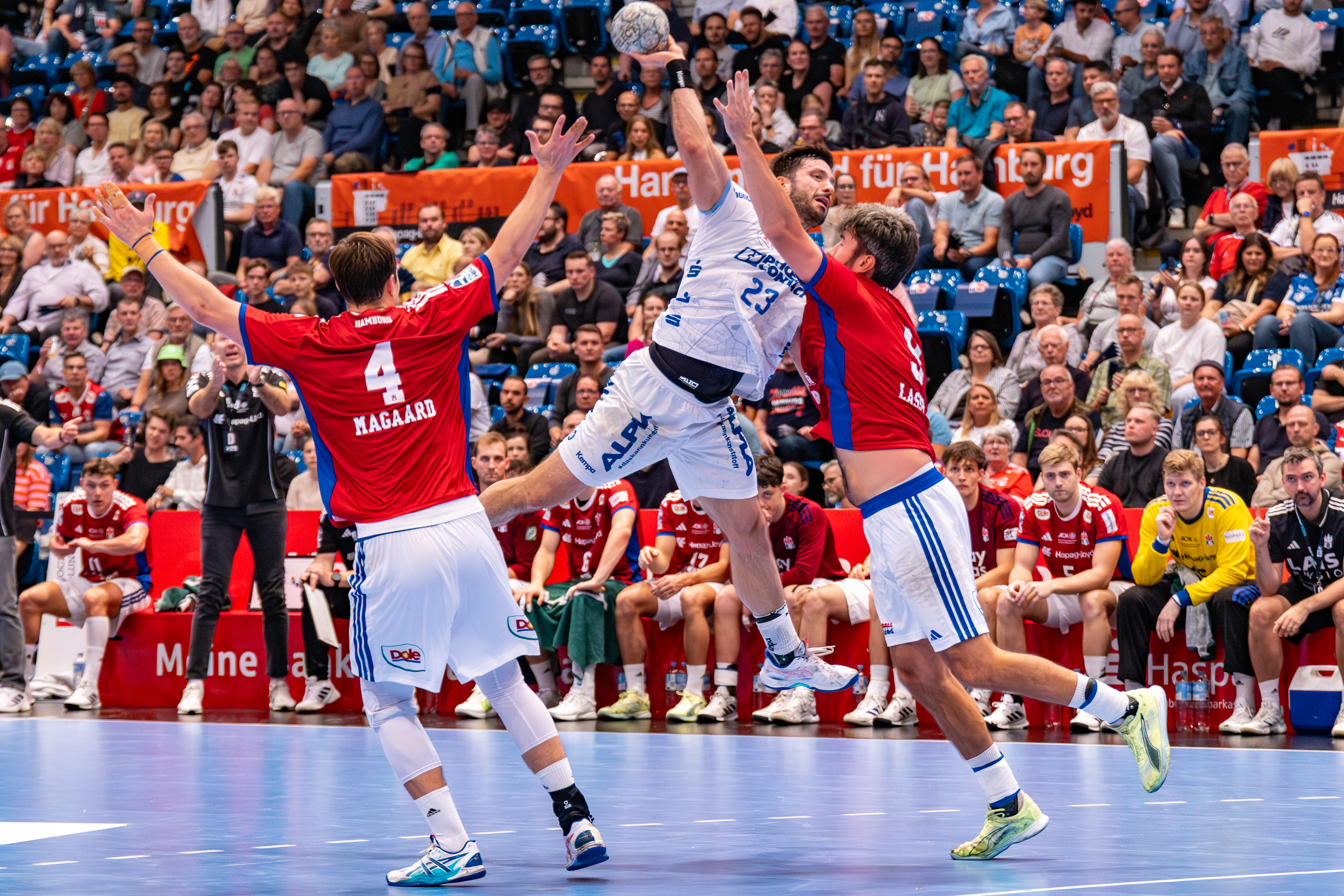 #23 Tim Suton (Rückraum Mitte) – TBV Lemgo Lippe jump high. #9 Jacob Lassen (Rückraum rechts) – Handball Sport Verein Hamburg block.