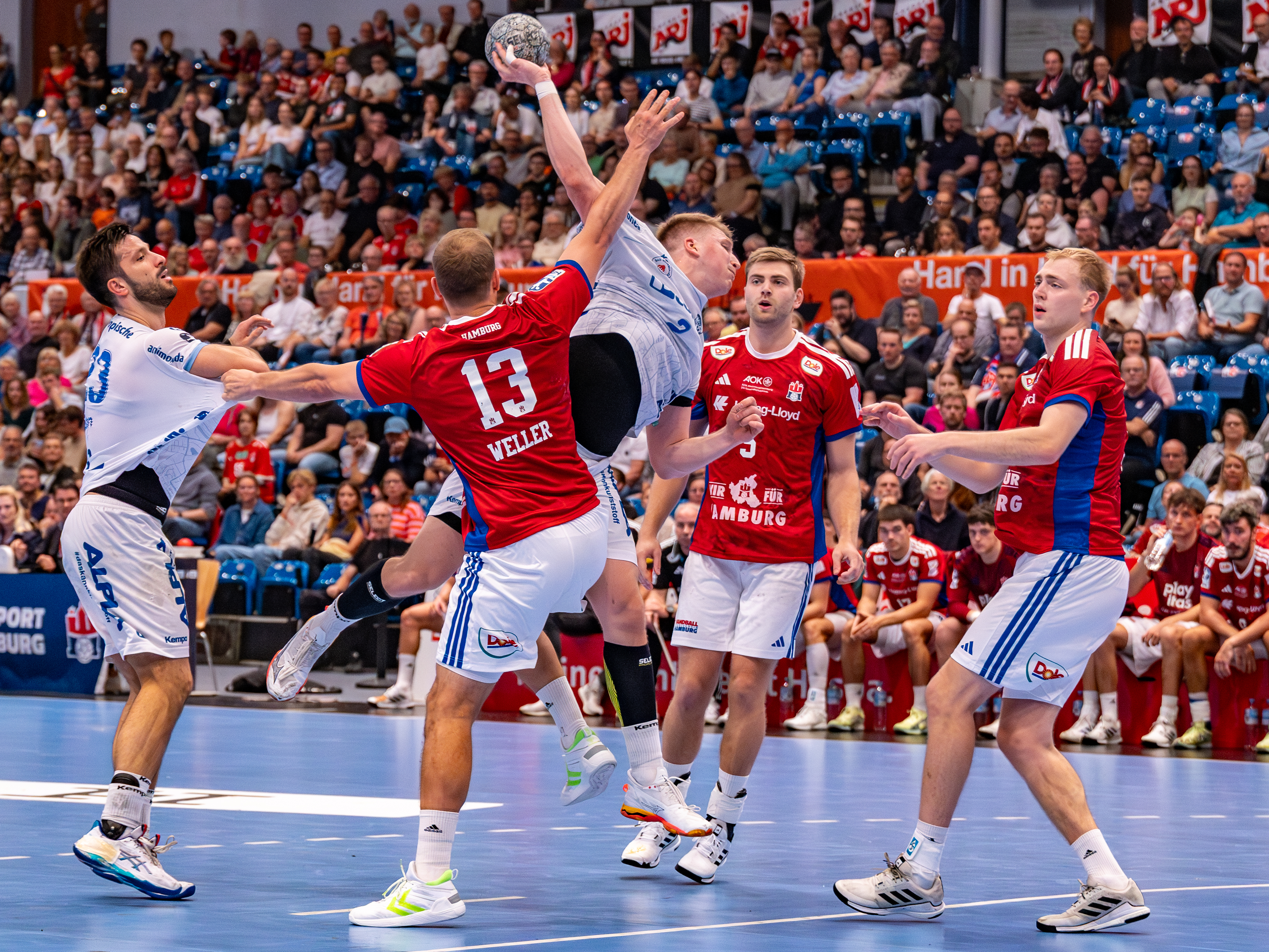 #2 Lukas Hutecek (Rückraum links) – TBV Lemgo Lippe shoots at goal. #13 Niklas Weller (Kreisläufer) – Handball Sport Verein Hamburg block