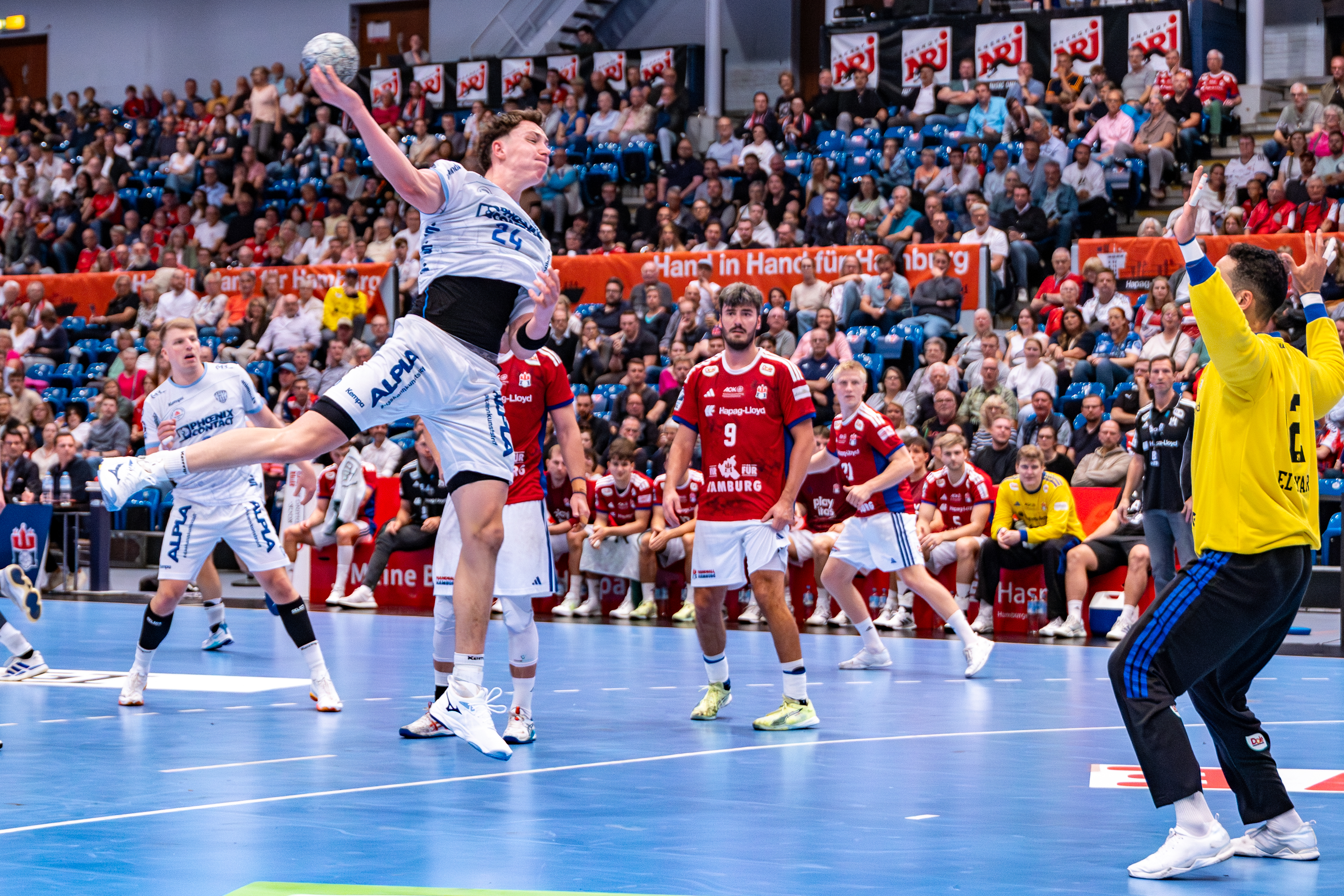 #24 Joel Willecke (Kreisläufer) – TBV Lemgo Lippe shoots at goal #12 Mohamed El-Tayar (Torwart) – Handball Sport Verein Hamburg