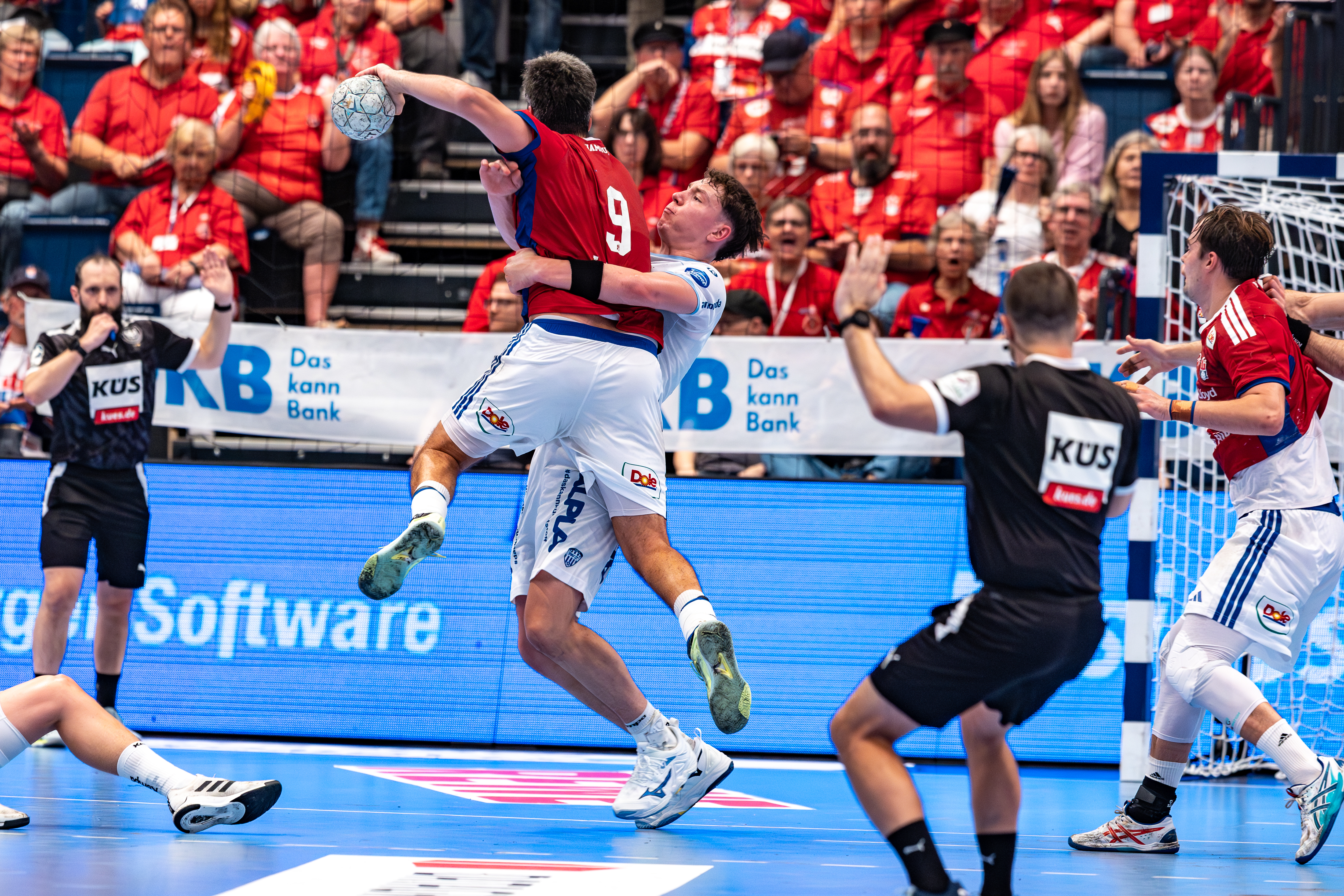 #9 Jacob Lassen (Rückraum rechts) – Handball Sport Verein Hamburg jump shoots at goal. #24 Joel Willecke (Kreisläufer) – TBV Lemgo Lippe block.
